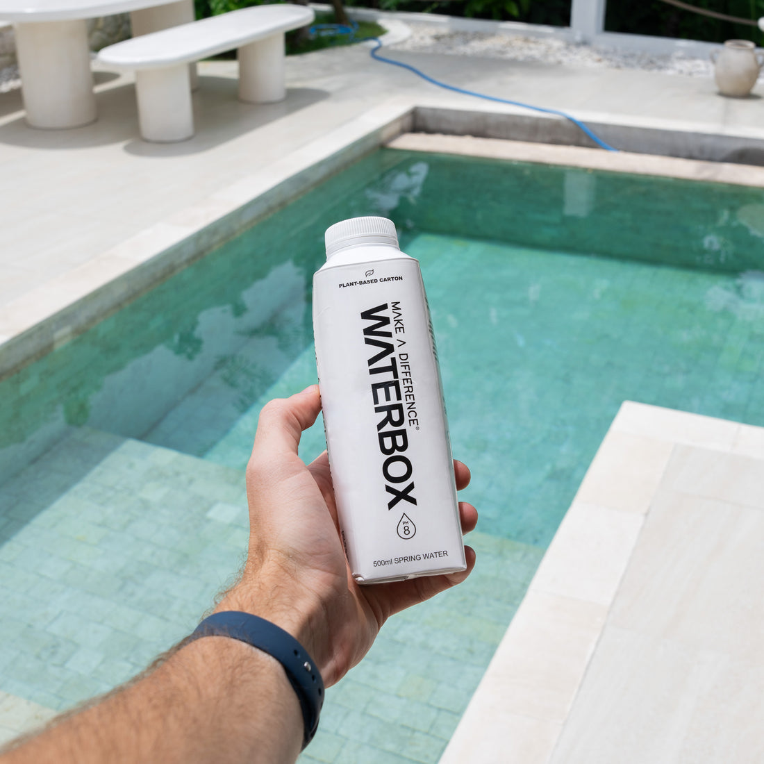 Waterbox Carton Held Against the Backdrop of a Sunlit Pool